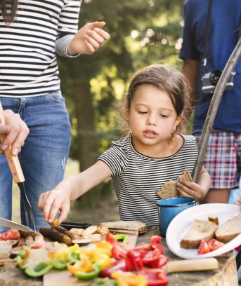 Beautiful family camping in forest, eating together.