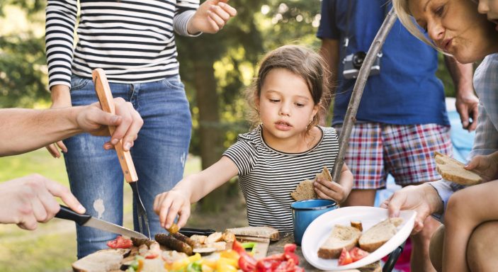 Beautiful family camping in forest, eating together.