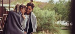 Holiday couple in hotel balcony wrapped in blanket