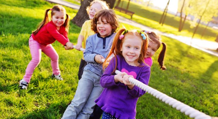Children play tug of war in the park.