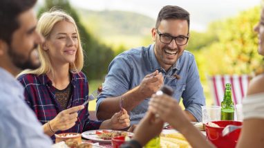Des amis profitent d'un repas après avoir cuisiné en camping.