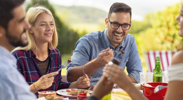 Des amis profitent d'un repas après avoir cuisiné en camping.